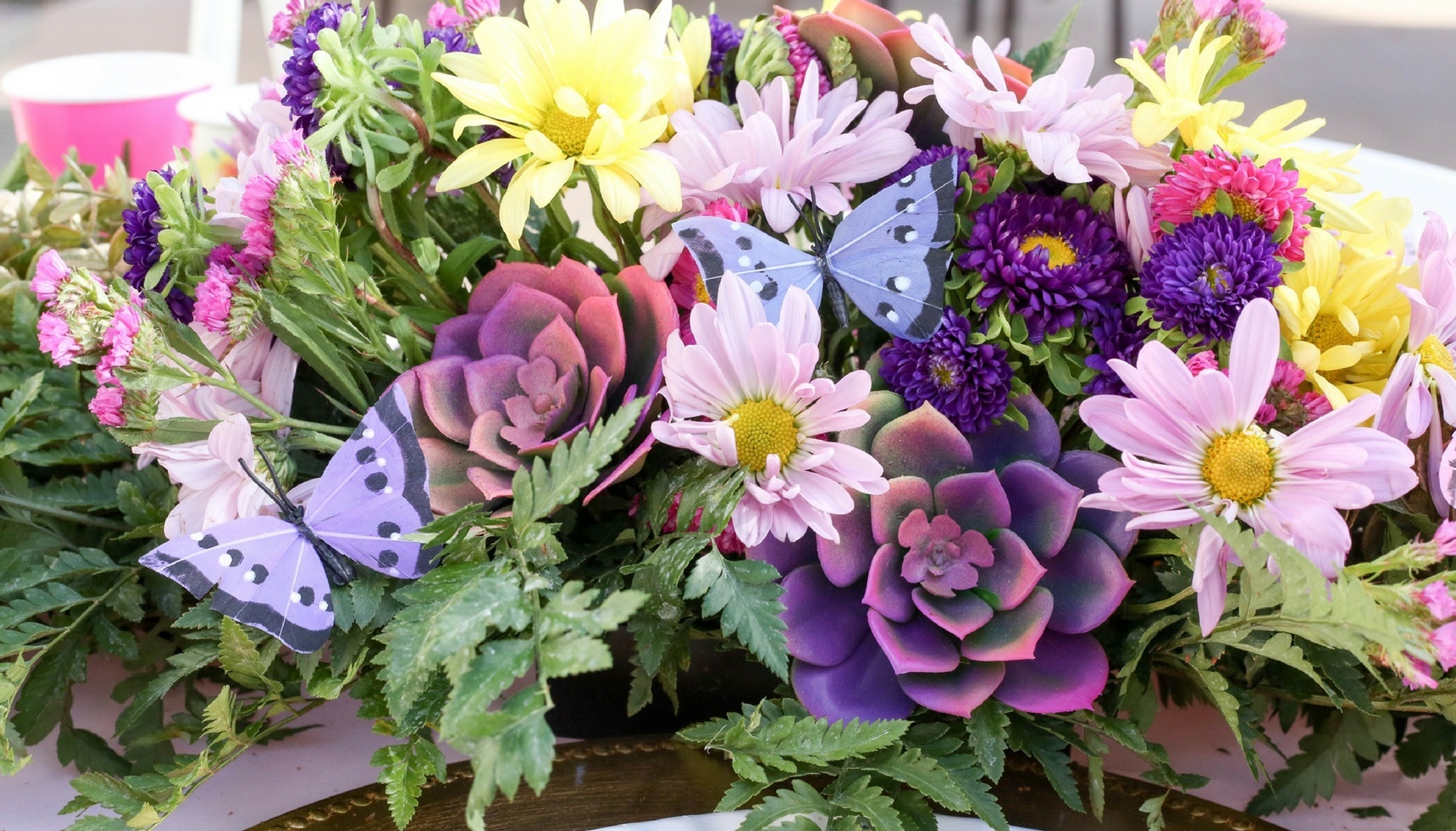 butterflies adorn a painted succulent and floral centerpiece