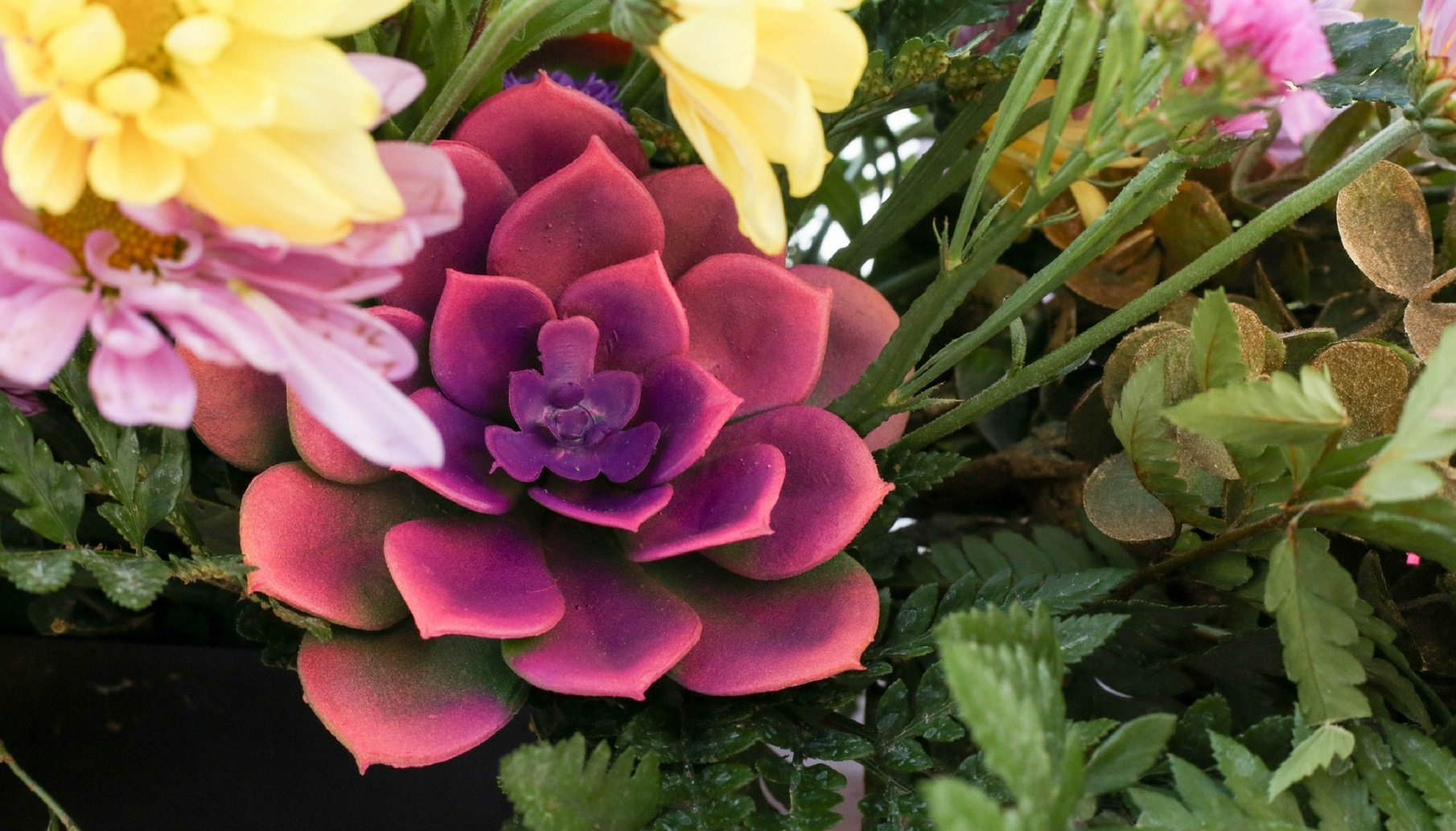 painted succulent is nestled into a fluorescent floral centerpiece