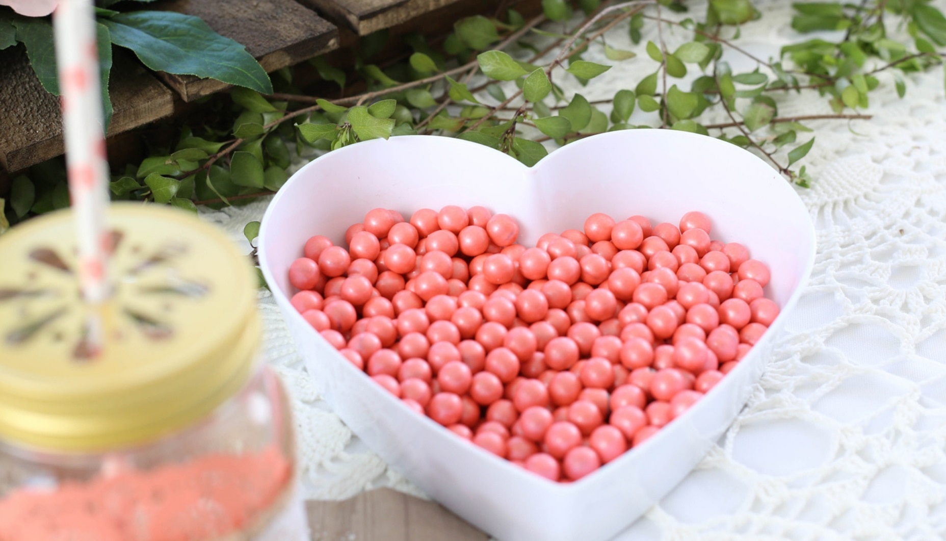 Heart shaped acrylic dish filled with coral colored sixlet chocolate candy