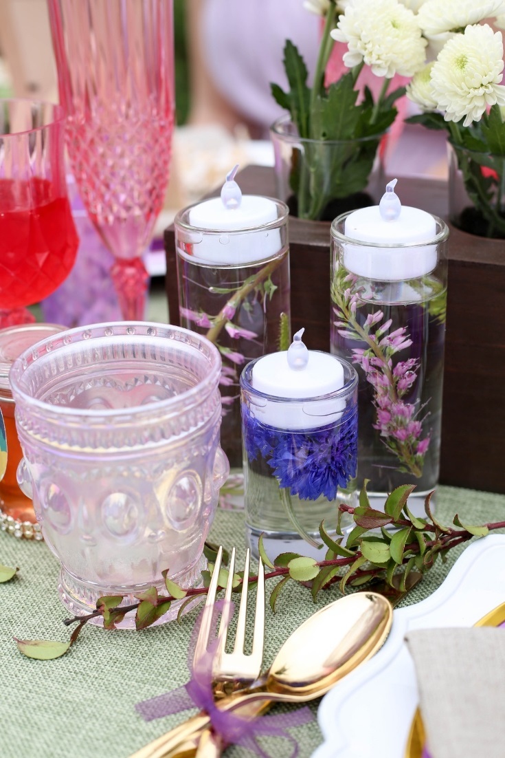 Wildflowers are submerged in fillable glass tea light holders and surrounded by wildflowers and iridescent vintage details.