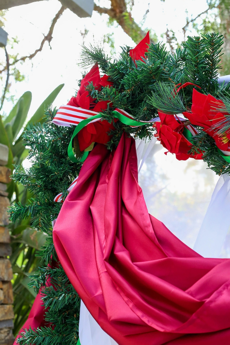 red draping fabric with pine garland and poinsettias