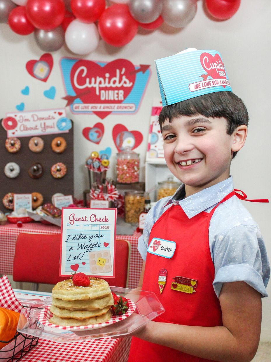 boy dressed as a diner waiter holding a stack of waffles