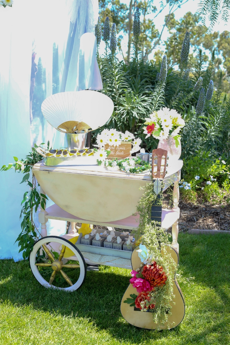 vintage tea cart holds ceremony items for guests to take as they enter a bohemian daisy themed wedding Boho chic wedding details with daisies.
