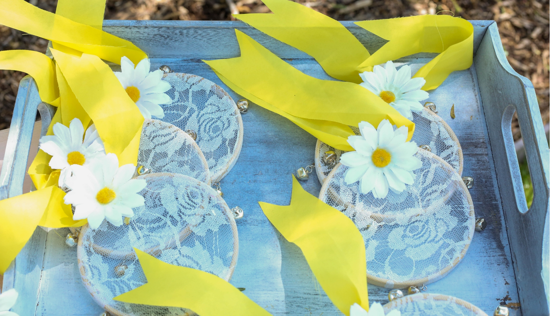hoop tambourines with daisies and yellow tails Lace hoop tambourines with silver bells, yellow tails and daisy embellishments for a musical wedding sendoff